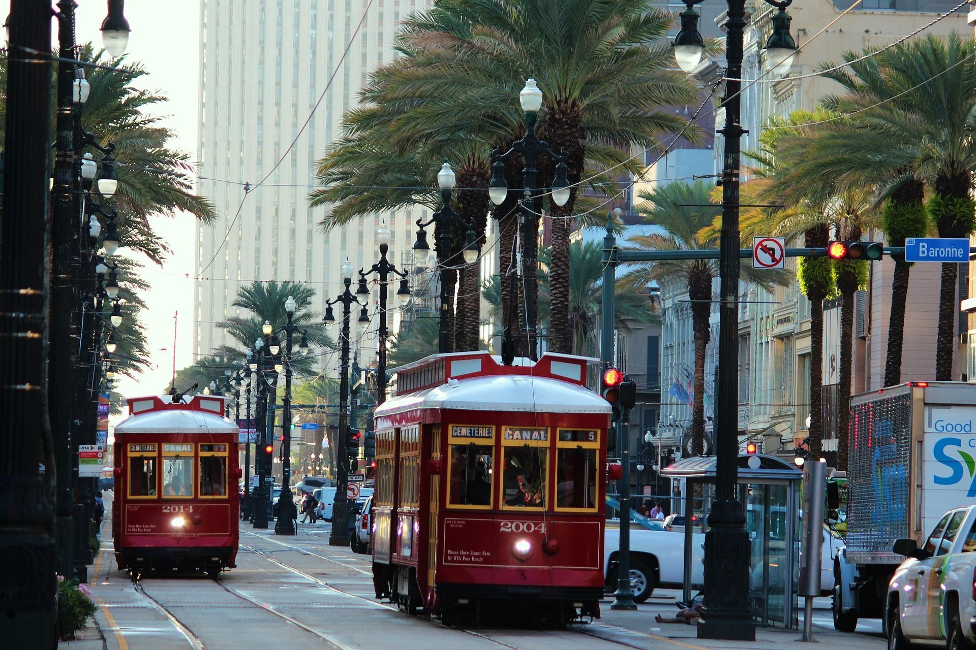 Two red trolleys are going down a street in a city