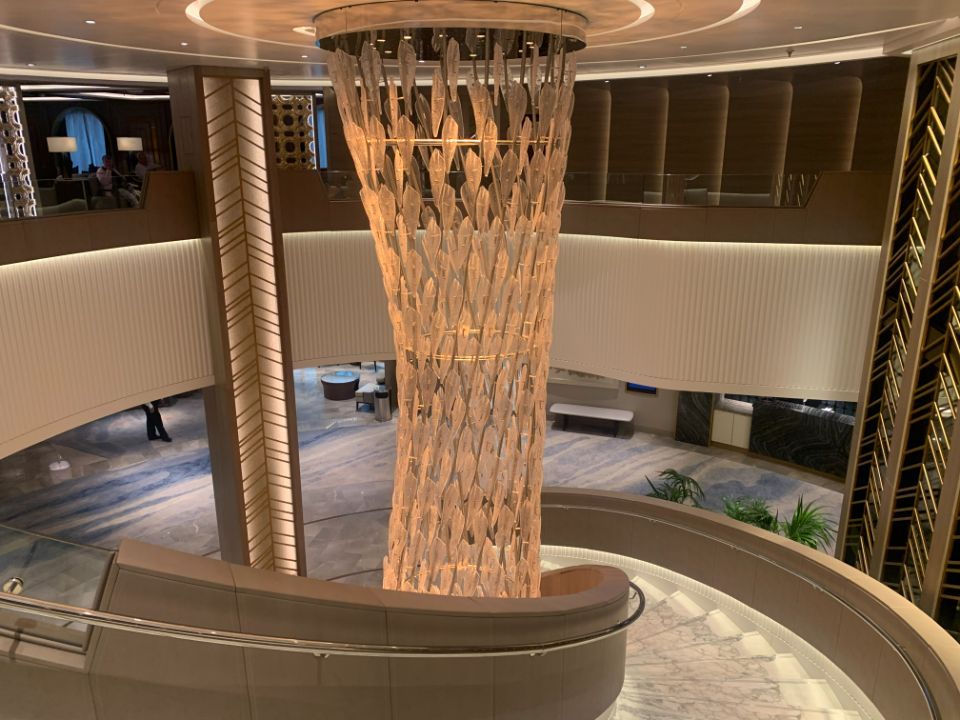 A large chandelier is hanging from the ceiling of a lobby.