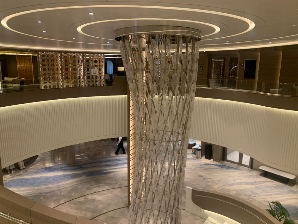 There is a large pillar in the middle of the lobby of a cruise ship