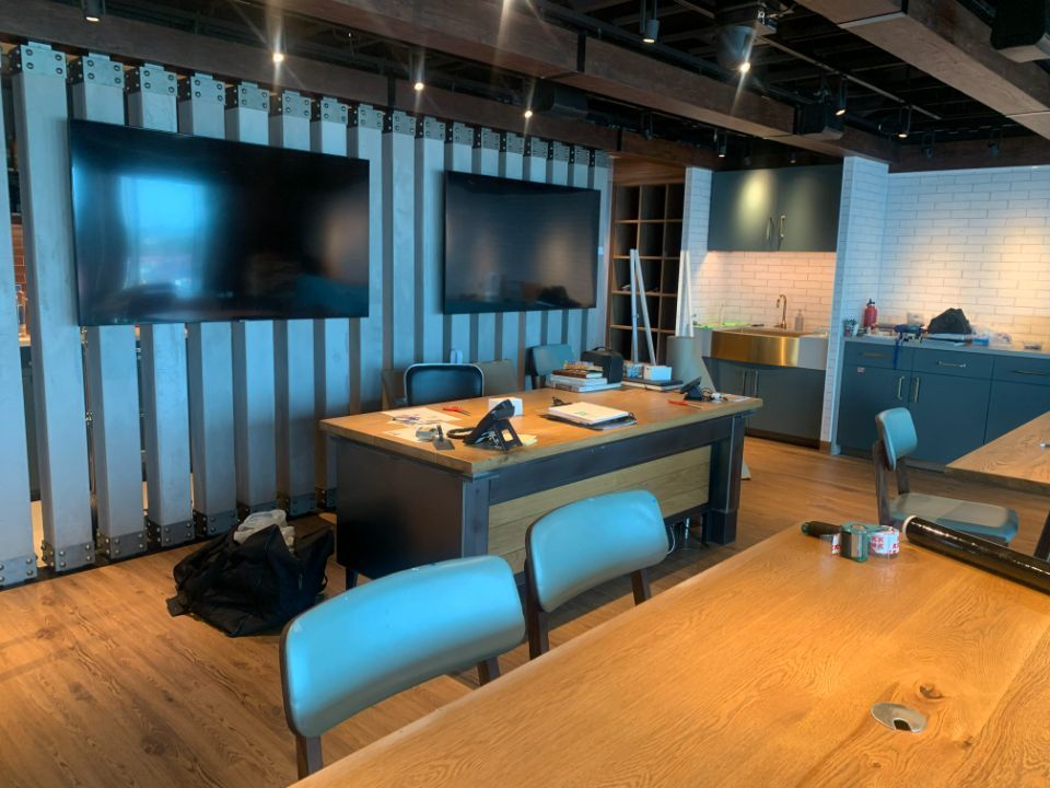 A conference room with a wooden table and chairs and a large flat screen tv on the wall.