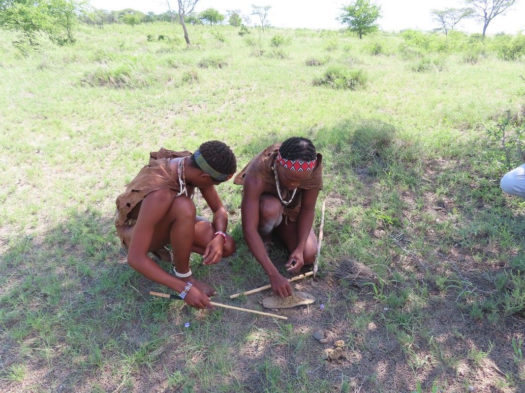 Two men are kneeling in the grass in a field.