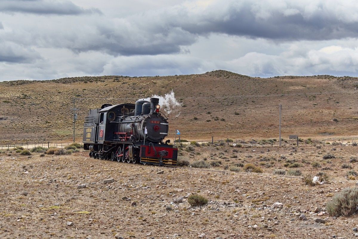 Steam engine train in arid landscape.
