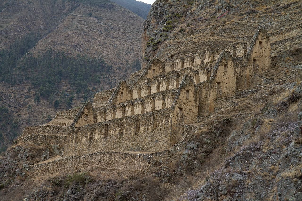 A row of stone buildings on the side of a mountain at Ollantaytambo, Peru