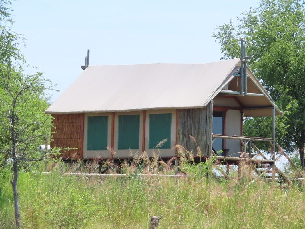 Namibian Chobe River Camp A small house is sitting in the middle of a grassy field.