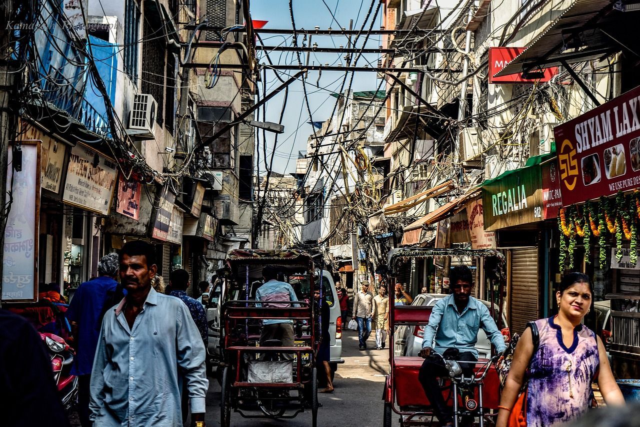 A man is riding a rickshaw down a narrow street in Delhi, india