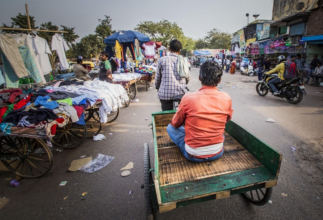 A man is sitting in the back of a cart at a market in delhi, india