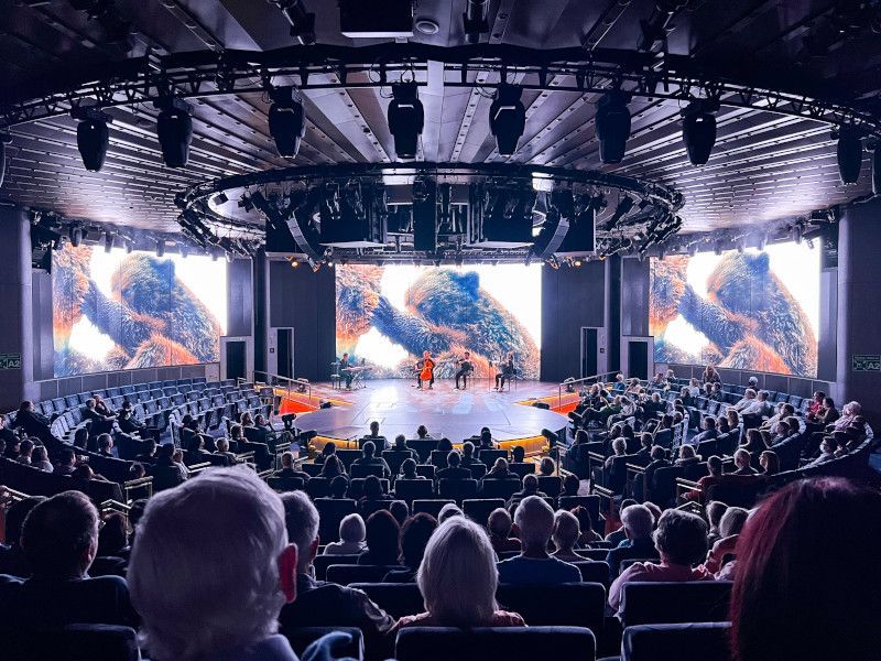 A large crowd of people are watching a show in a theater on  Koningsdam cruise ship