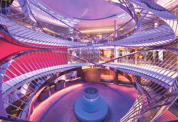 a spiral staircase in a building with purple lights the atrium onboard Koningsdam