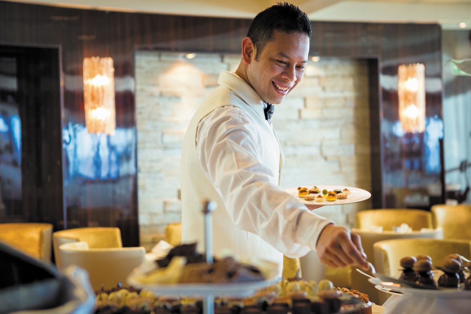 A man in a white shirt is serving food in a restaurant called la veranda