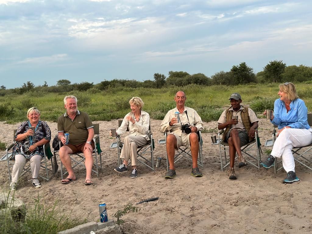 A group of people are sitting in folding chairs on the beach.