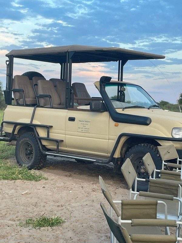 A safari vehicle is parked next to a row of chairs.