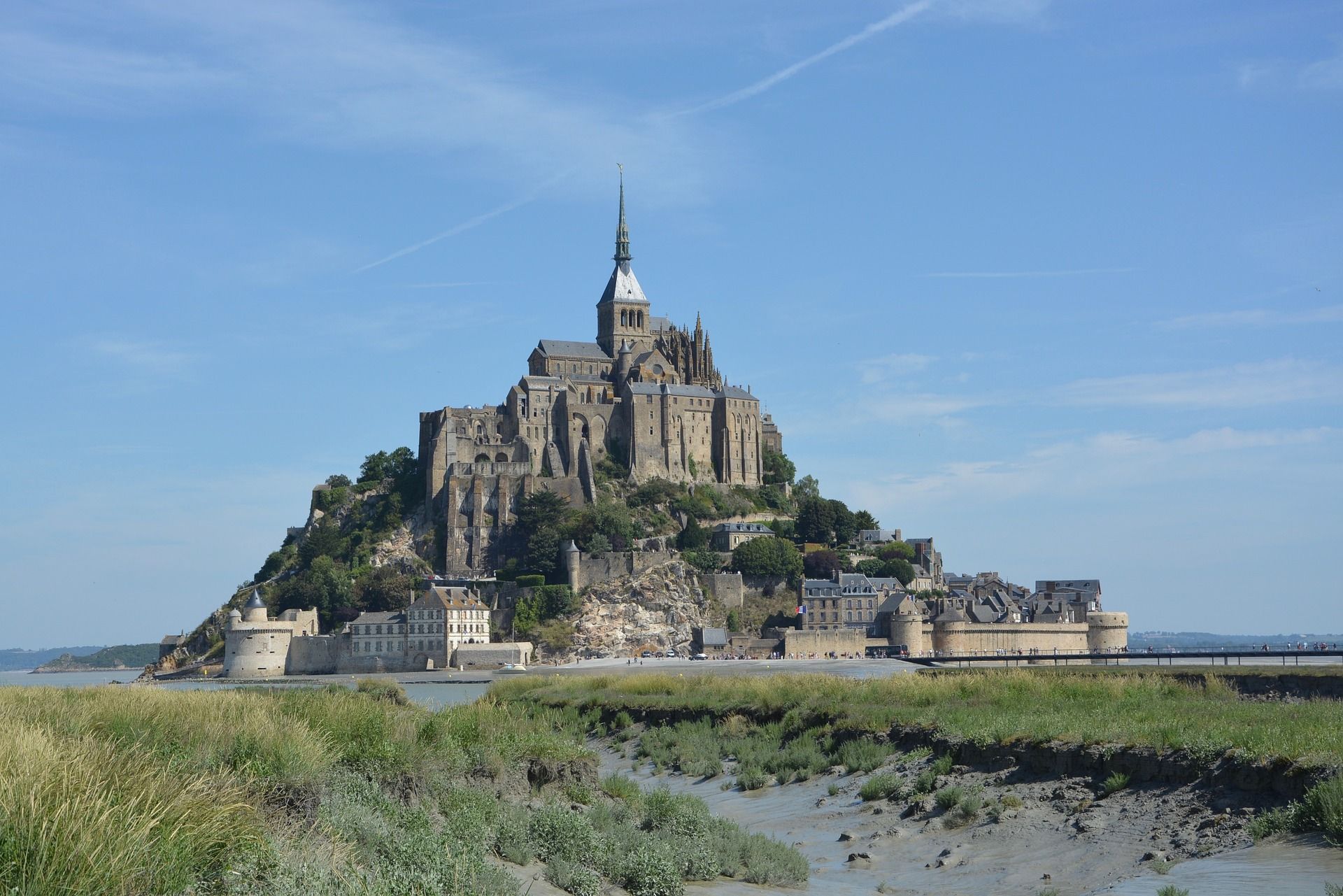 A large castle sits on top of a hill overlooking a body of water