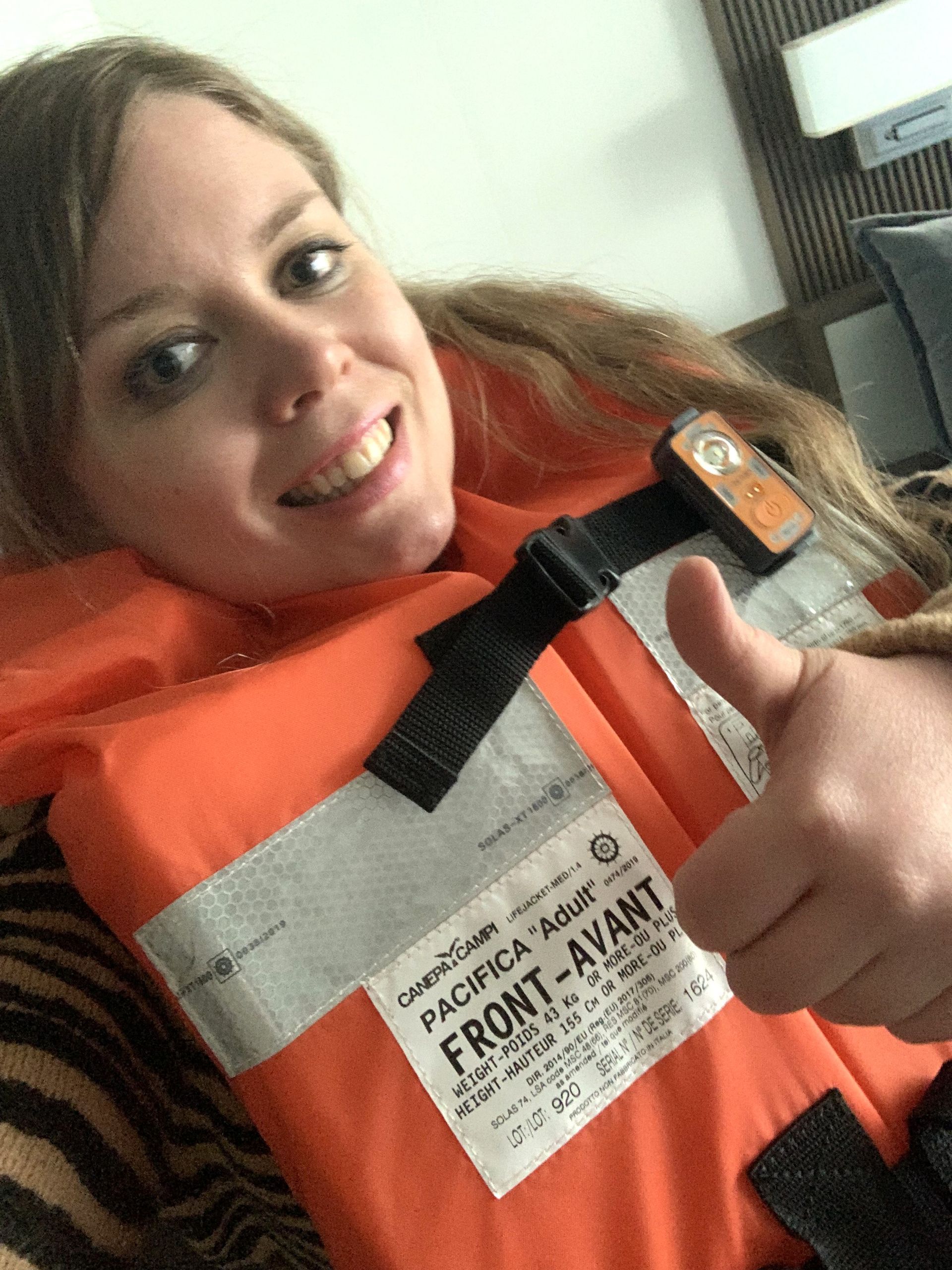 A woman wearing a life jacket is giving a thumbs up