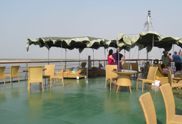 A boat deck with tables and chairs and umbrellas