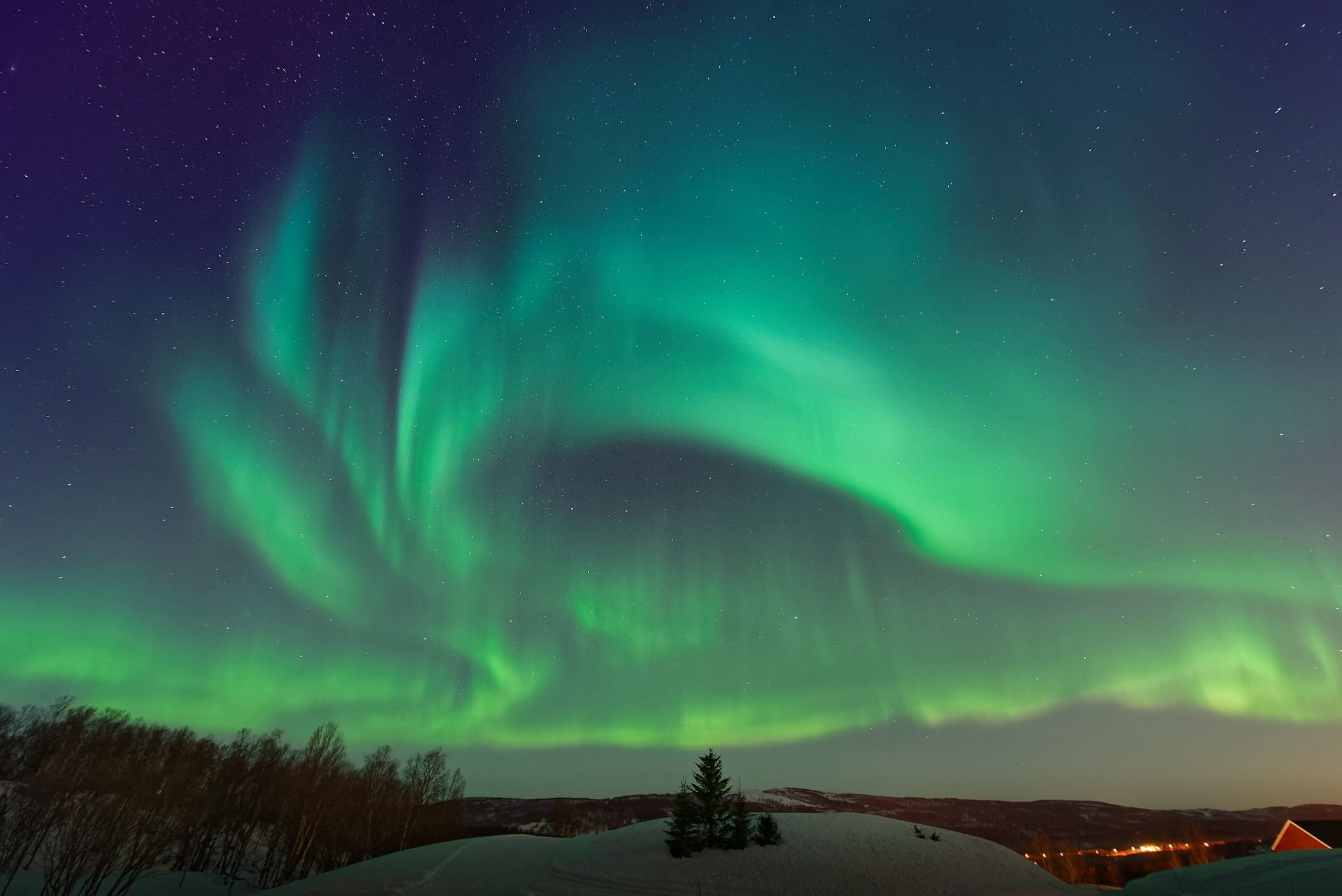 The aurora borealis is dancing in the night sky over a snowy landscape.