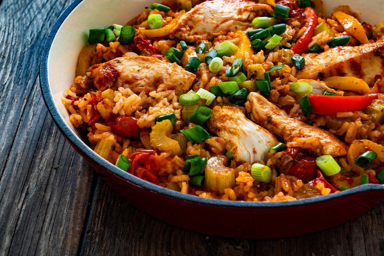 A pan filled with rice and chicken on a wooden table.