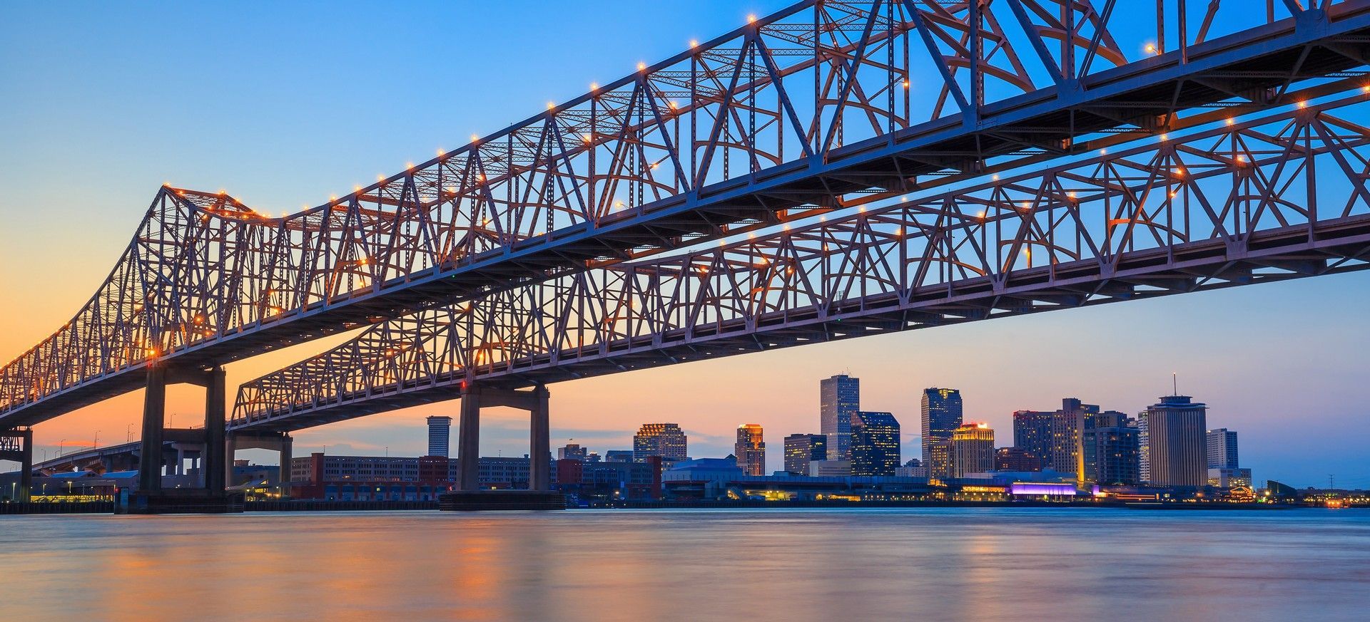 A bridge over a body of water with a city skyline in the background.