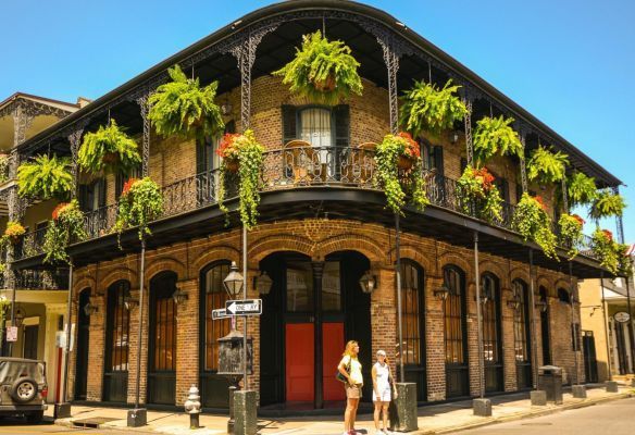 New Orleans, USA, two women are standing in front of a brick building with ferns hanging from the balconies 