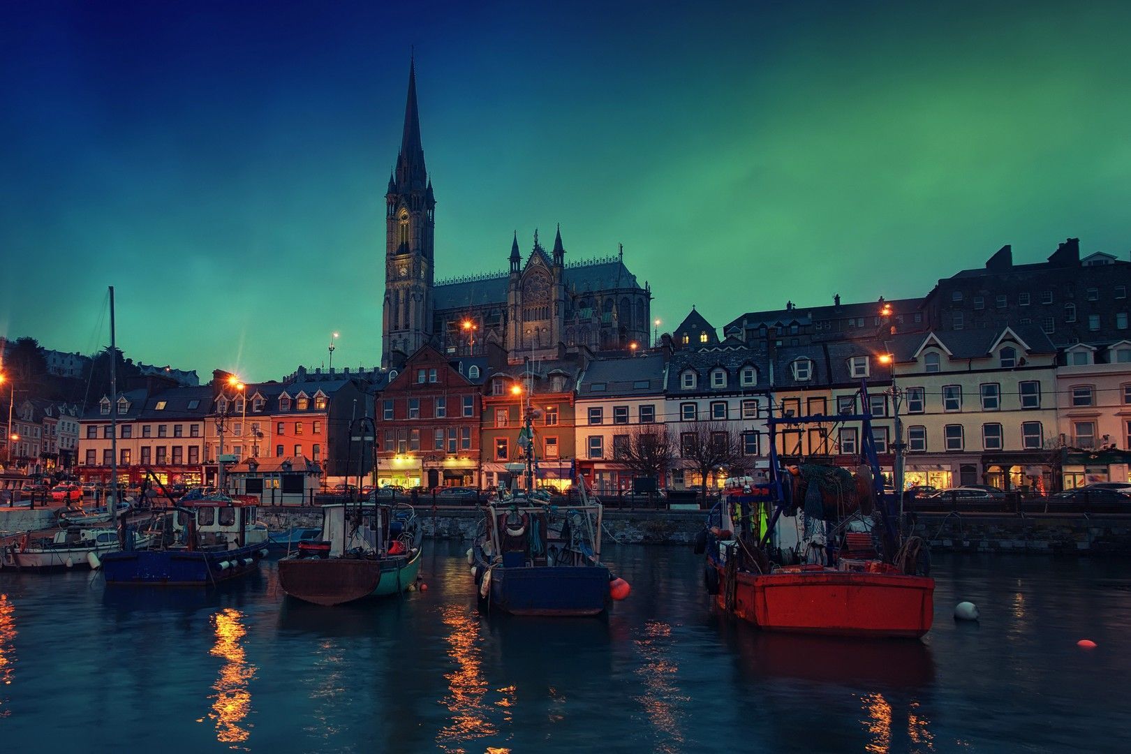 A city at night with boats in the water and a church in the background.