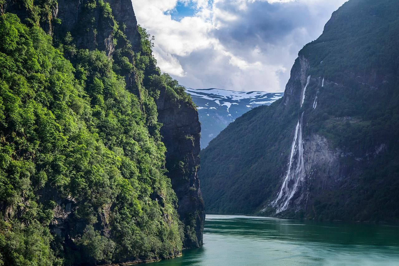 A river surrounded by mountains and trees with a waterfall in the middle