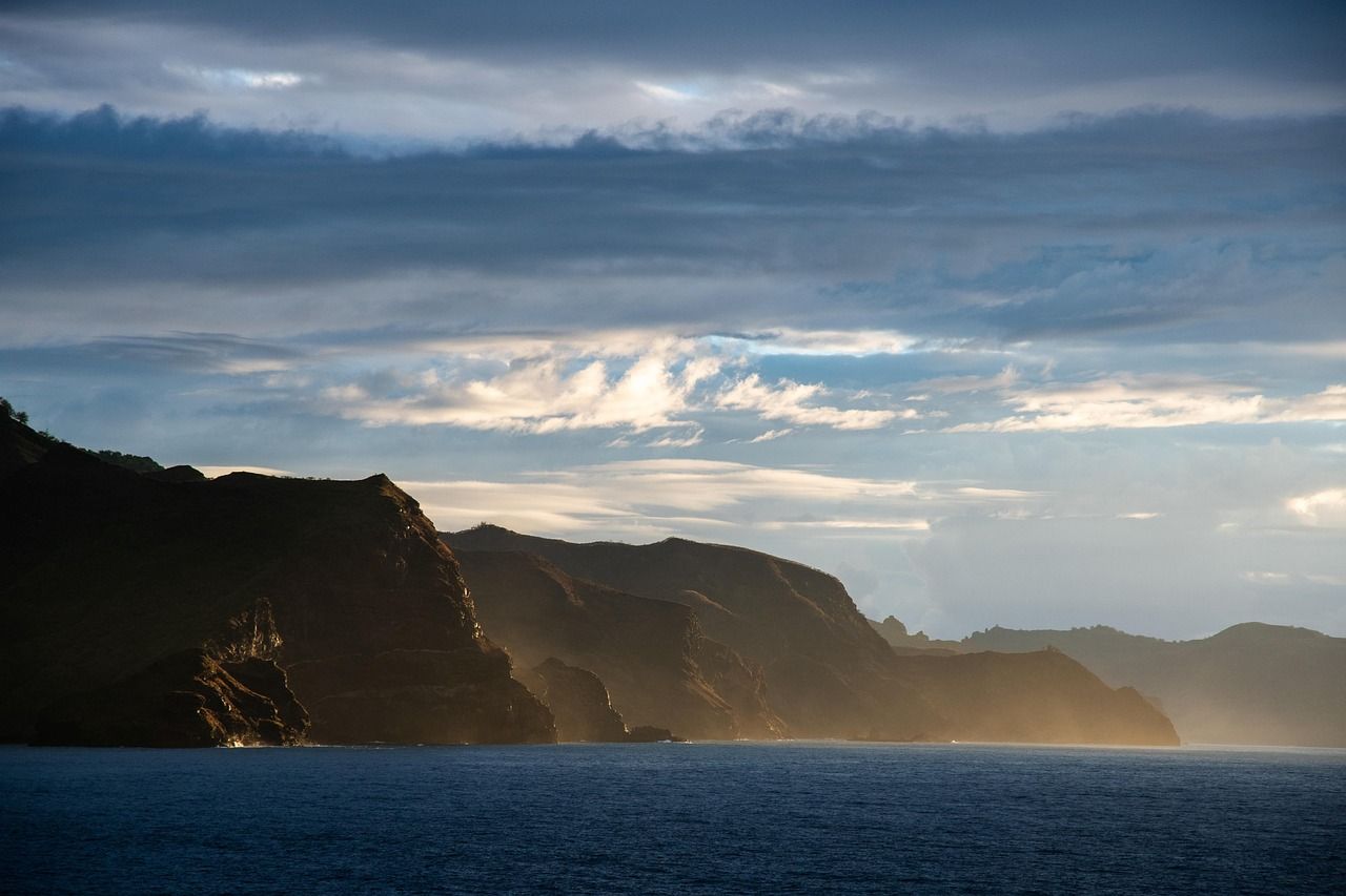 A large body of water with mountains in the background and a cloudy sky.