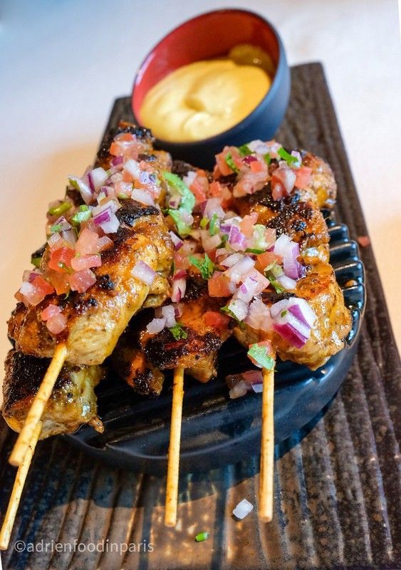 A close up of a plate of nikkei food with a bowl of dipping sauce