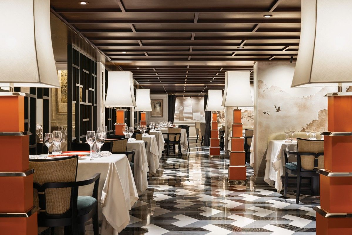 A long dining room with tables and chairs and lamps