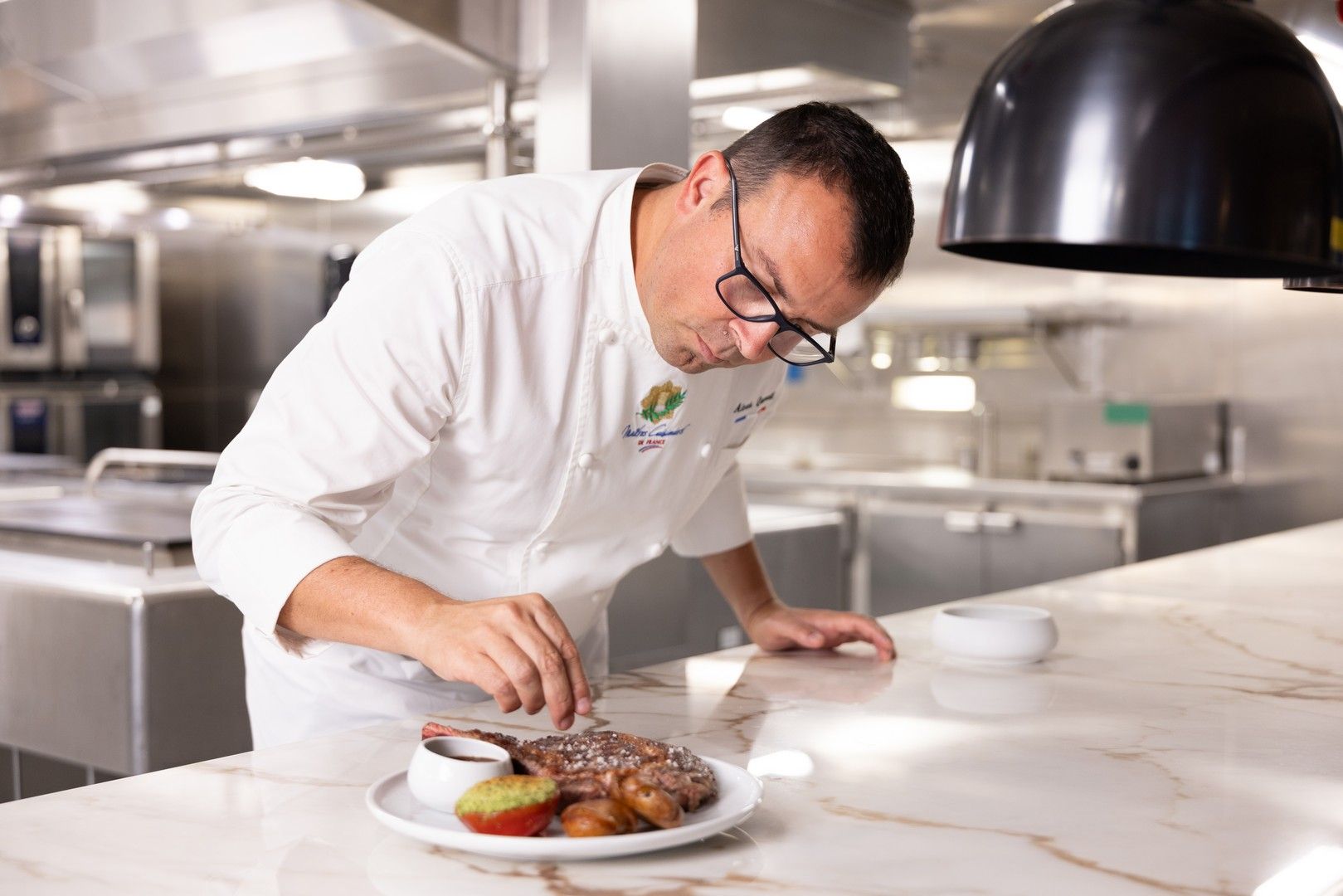 A chef is preparing a plate of food in a kitchen.