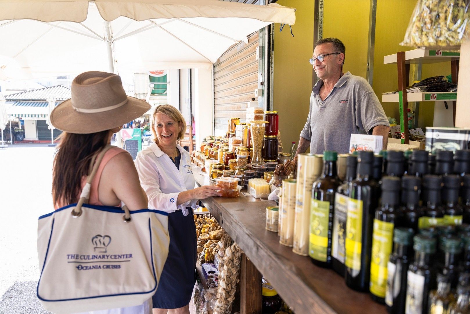 A woman in a hat is talking to a man in a store oceania culinary discovery tour