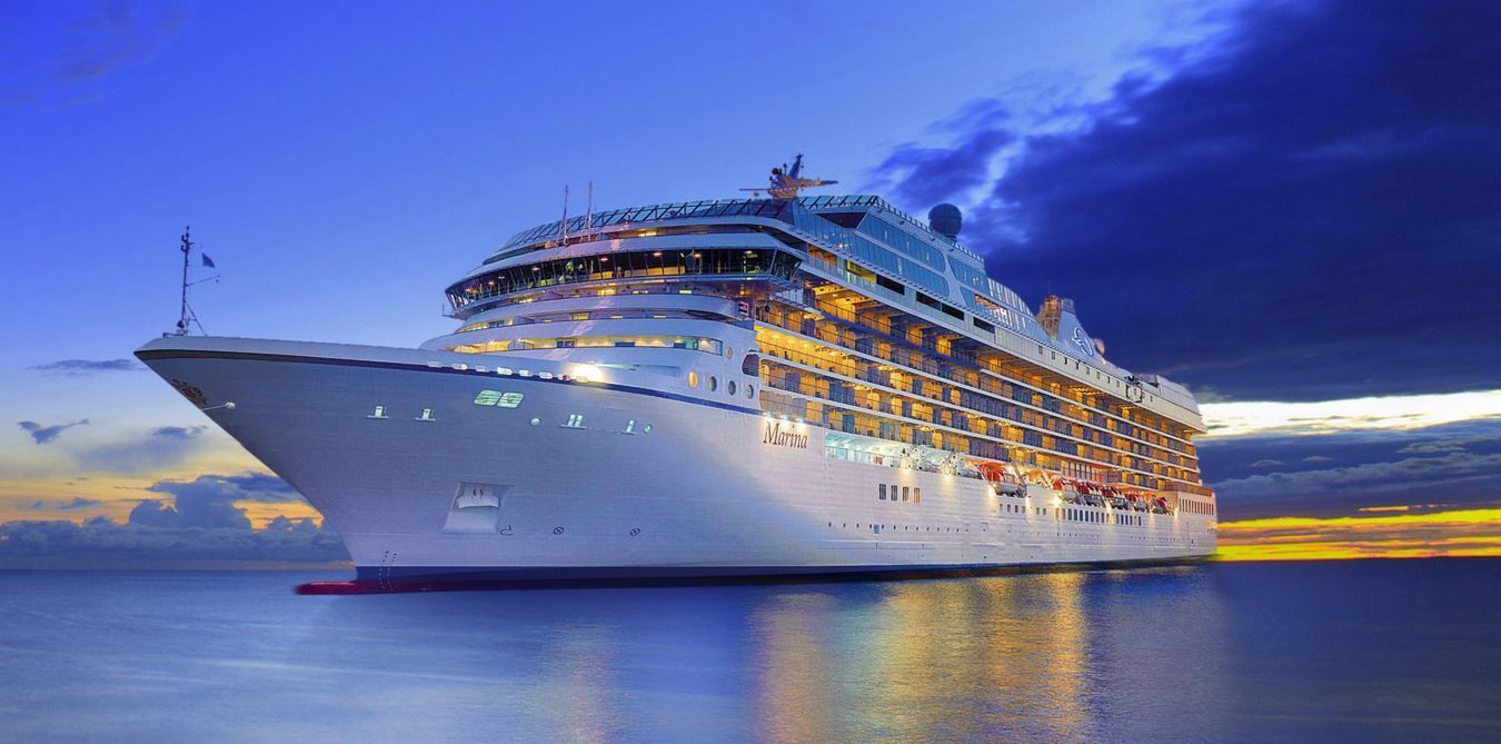 A large cruise ship is docked in the ocean at sunset.