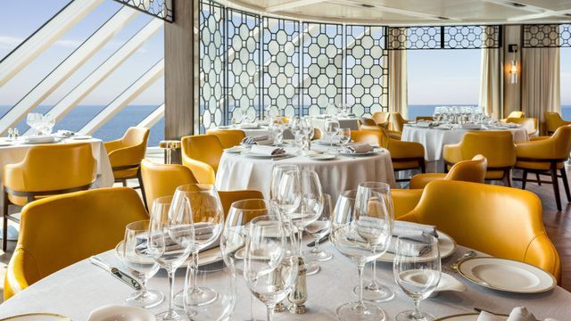 a restaurant with tables and chairs set for a meal with a view of the ocean on Oceania Cruises