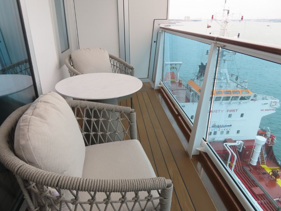 A balcony on a cruise ship with a table and chairs