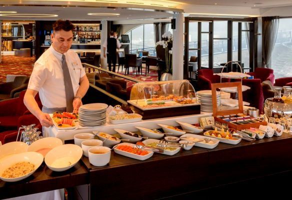 a man is preparing food at a buffet table in the Panorama Bistro restaurant on Avalon Envision