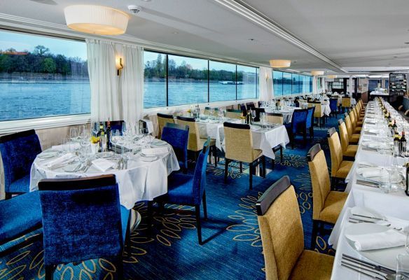 there are many tables and chairs in the 
 Panorama Restaurant with a view of the water .