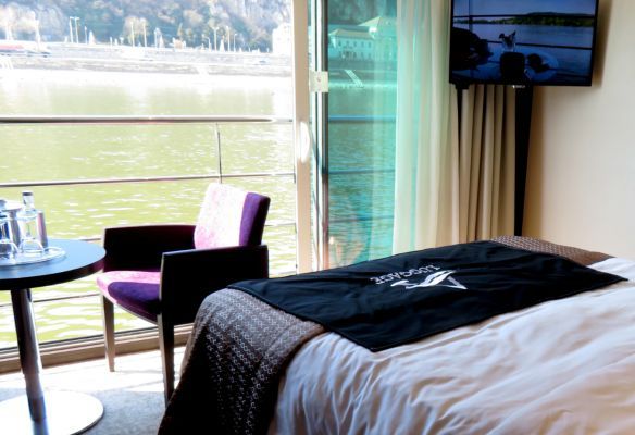 a river cruise Panorama suite with a bed , chair , table and television on Avalon Envision