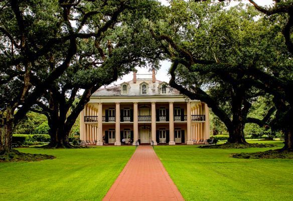 a large house with a red brick walkway leading to it is surrounded by trees Traditional Plantation House, USA