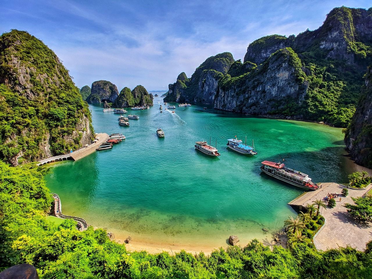 A large body of water surrounded by mountains and trees with boats in it. ha long bay