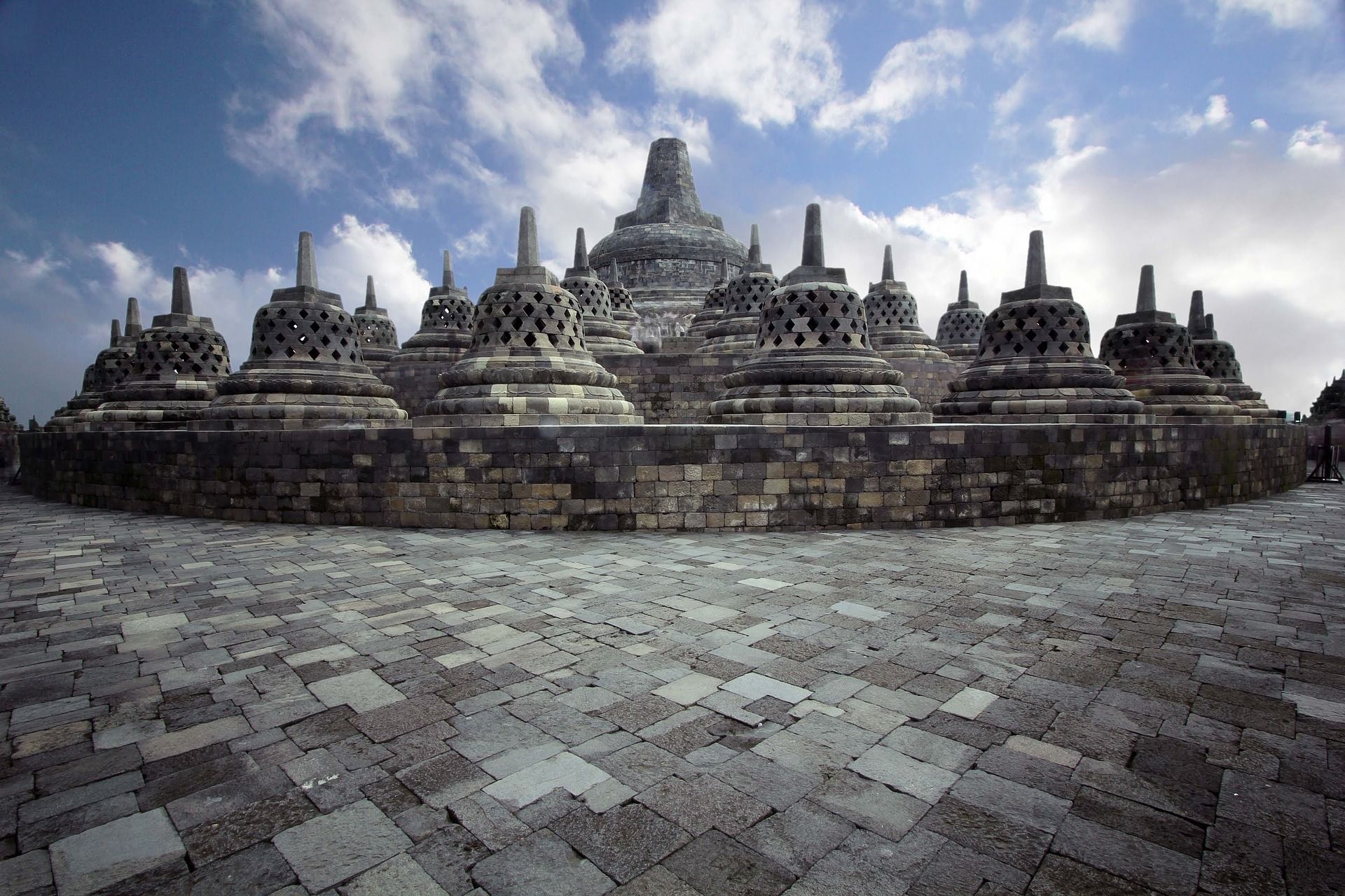 A brick walkway leading to a temple with a blue sky in the background