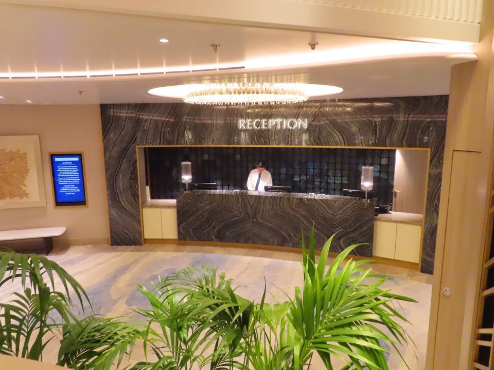 A man stands behind a reception desk in a hotel lobby