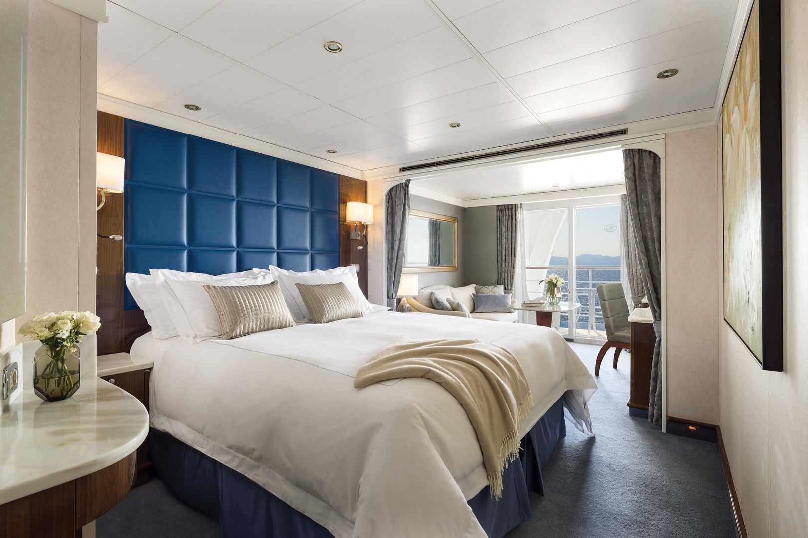 A cruise room with a large bed and a balcony on board seven seas voyager