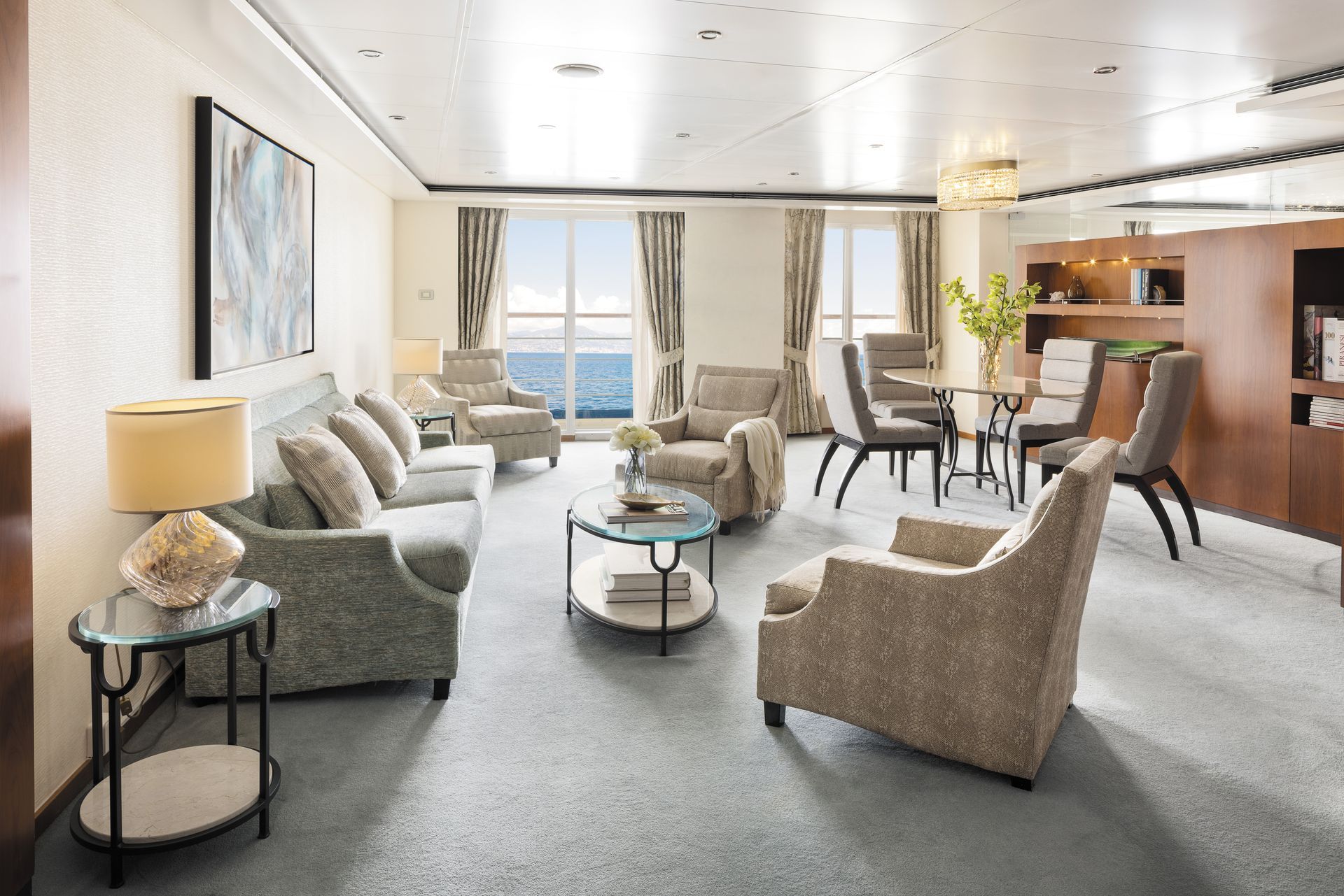 A living room filled with furniture and a table with a view of the ocean onboard regent seven seas voyager