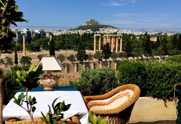 A table with a lamp and a chair with a view of Athens