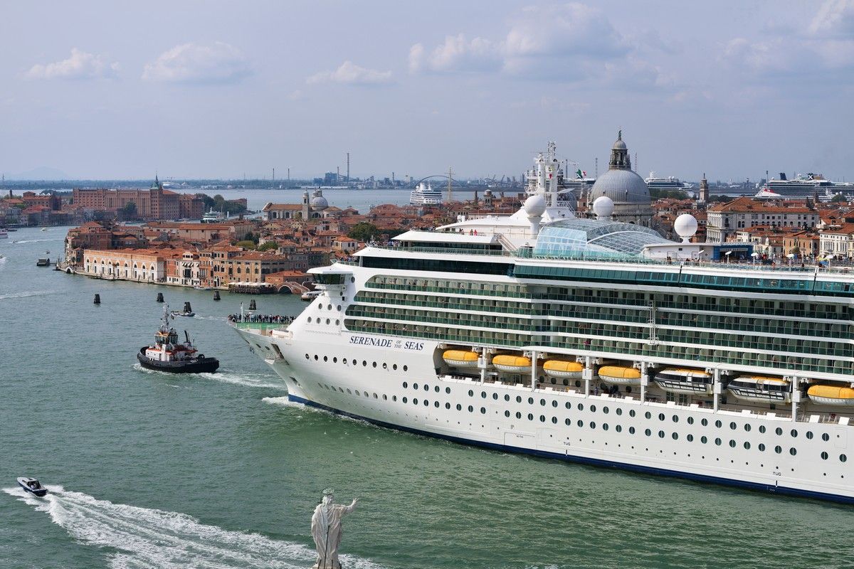 A royal caribbean cruise ship is docked in the water near a city on a world cruise