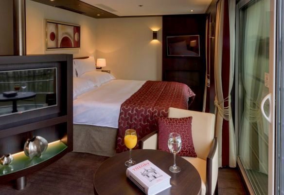 a Royal Suite with a bed and a table with a book on it on board Avalon Envision