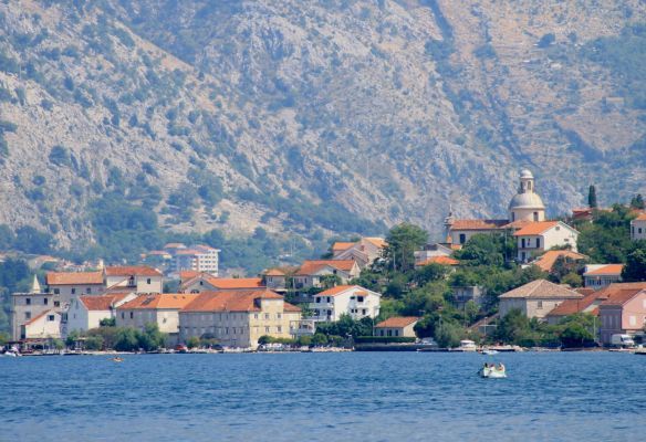 A small town sits on the shore of a lake with mountains in the background.