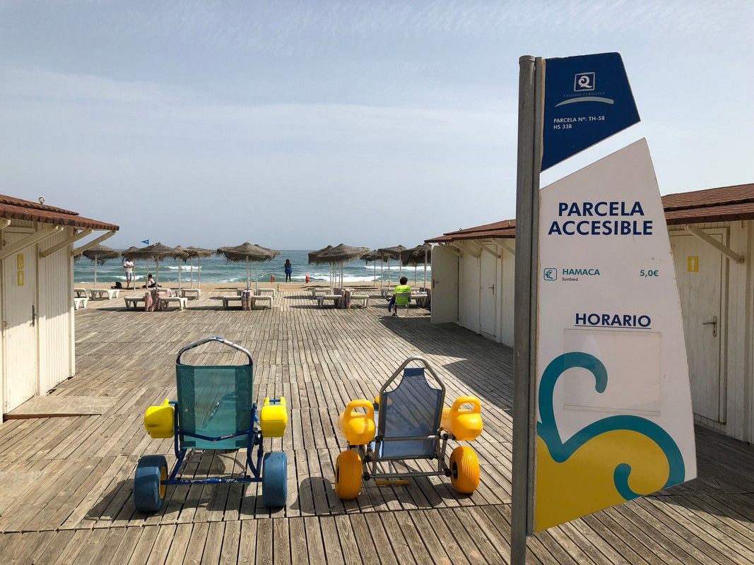 Two wheelchairs are sitting on a wooden deck next to a sign that says parcela accessible.