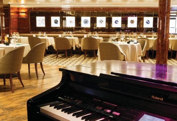 A piano is sitting in front of a restaurant with tables and chairs