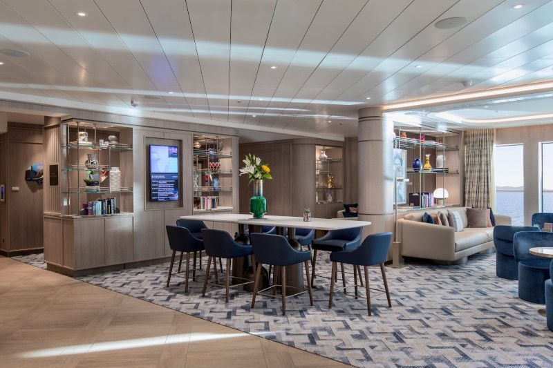 A large living room with a table and chairs on a cruise ship on Silver Nova cruise ship