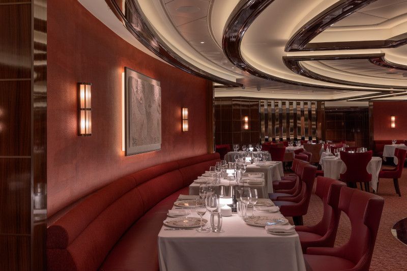 A large dining room with tables and chairs set for dinner on Silver Nova cruise ship