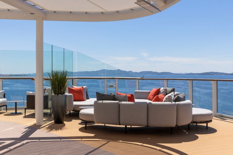 A large couch is sitting on a balcony overlooking the ocean on Silver Nova cruise ship